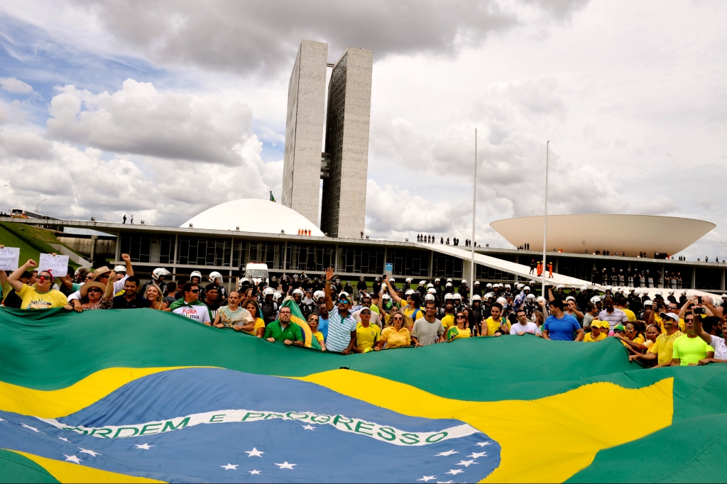 Manifestantes se reúnem em torno da bandeira do Brasil, com o Congresso Nacional ao fundo